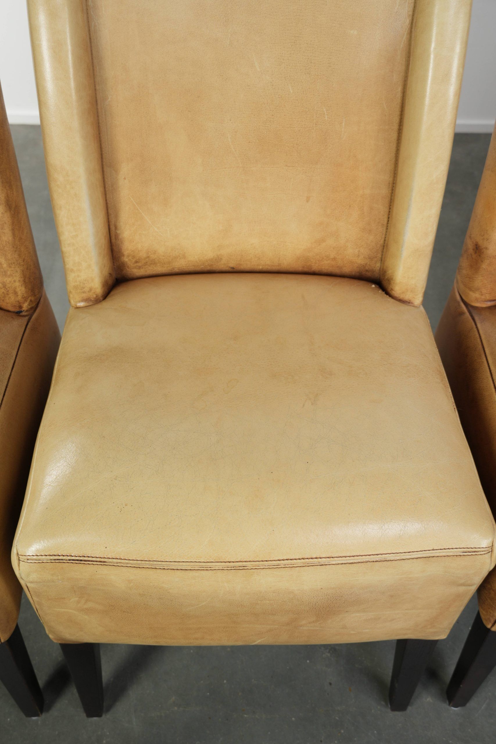 Ensemble de quatre chaises de salle à manger en cuir de vache avec un siège confortable et un dossier haut.