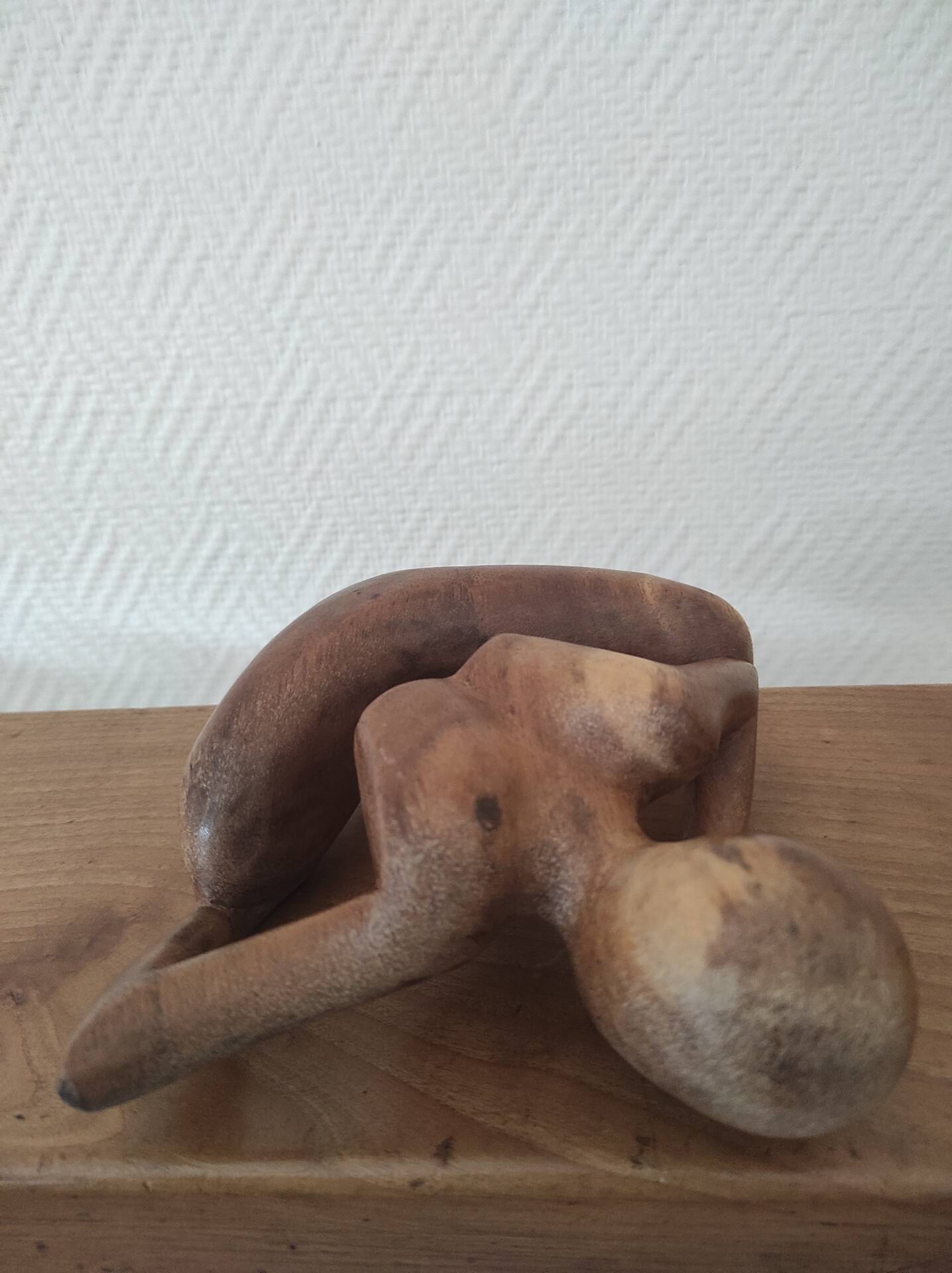 Wooden sculpted statuette of a woman in a pensive pose.