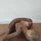 Wooden sculpted statuette of a woman in a pensive pose.