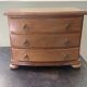 Blonde wooden doll's chest with brass handles.