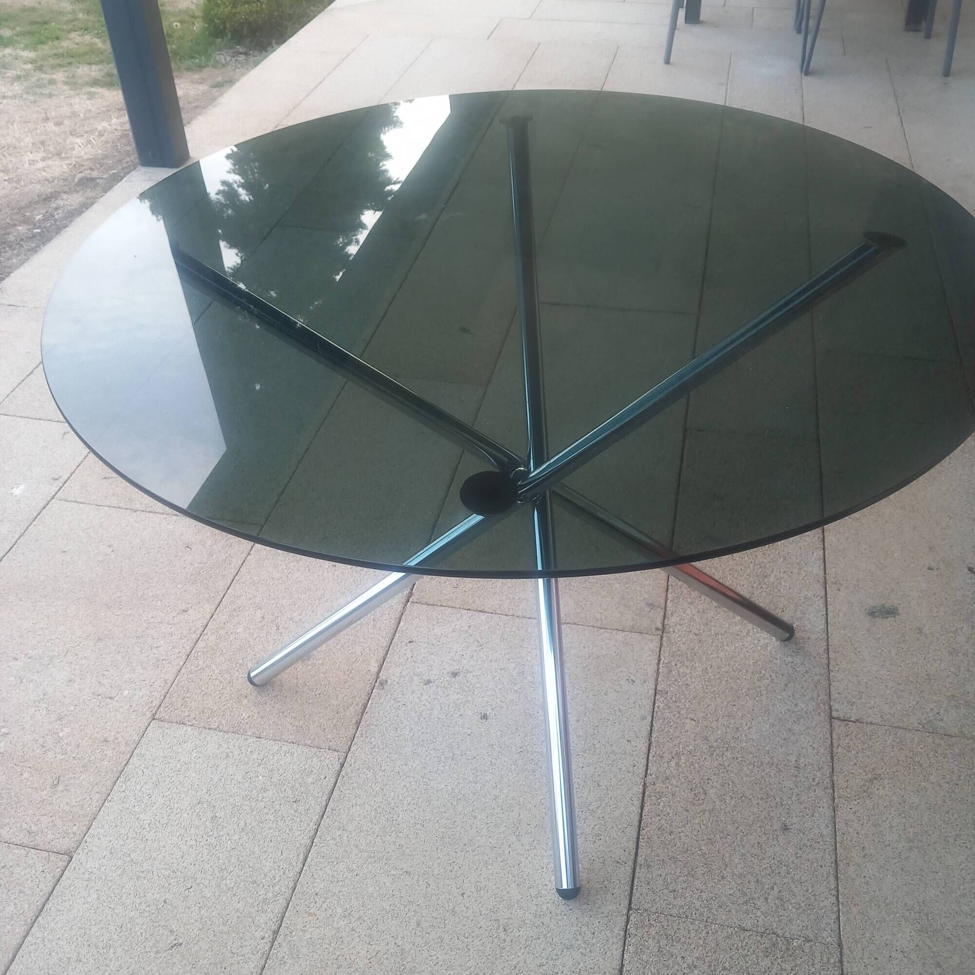 Round smoked glass table from the 70s. Foldable stainless steel legs.