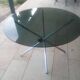 Round smoked glass table from the 70s. Foldable stainless steel legs.