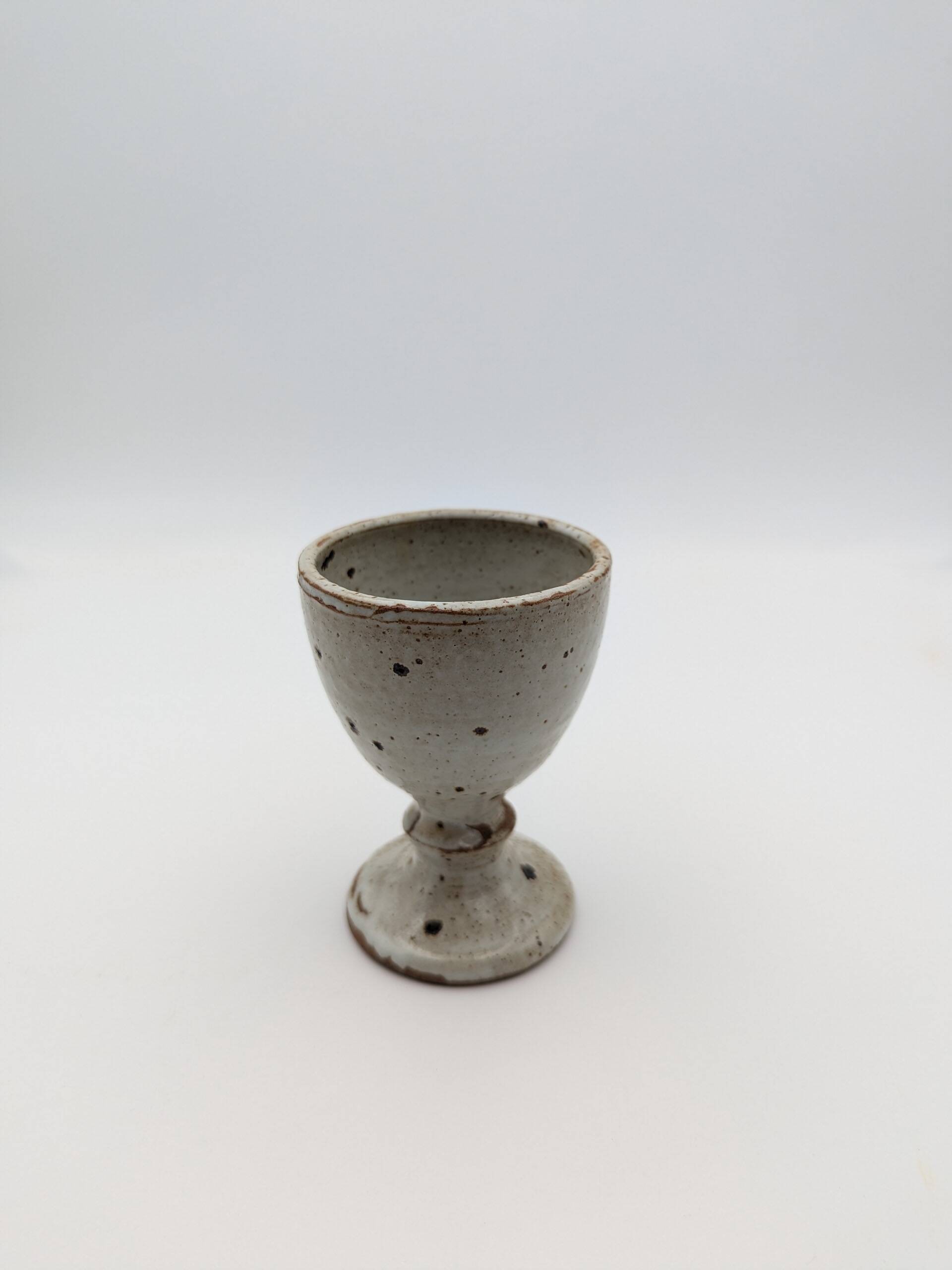 Glass on foot in pearly white stoneware with black spots