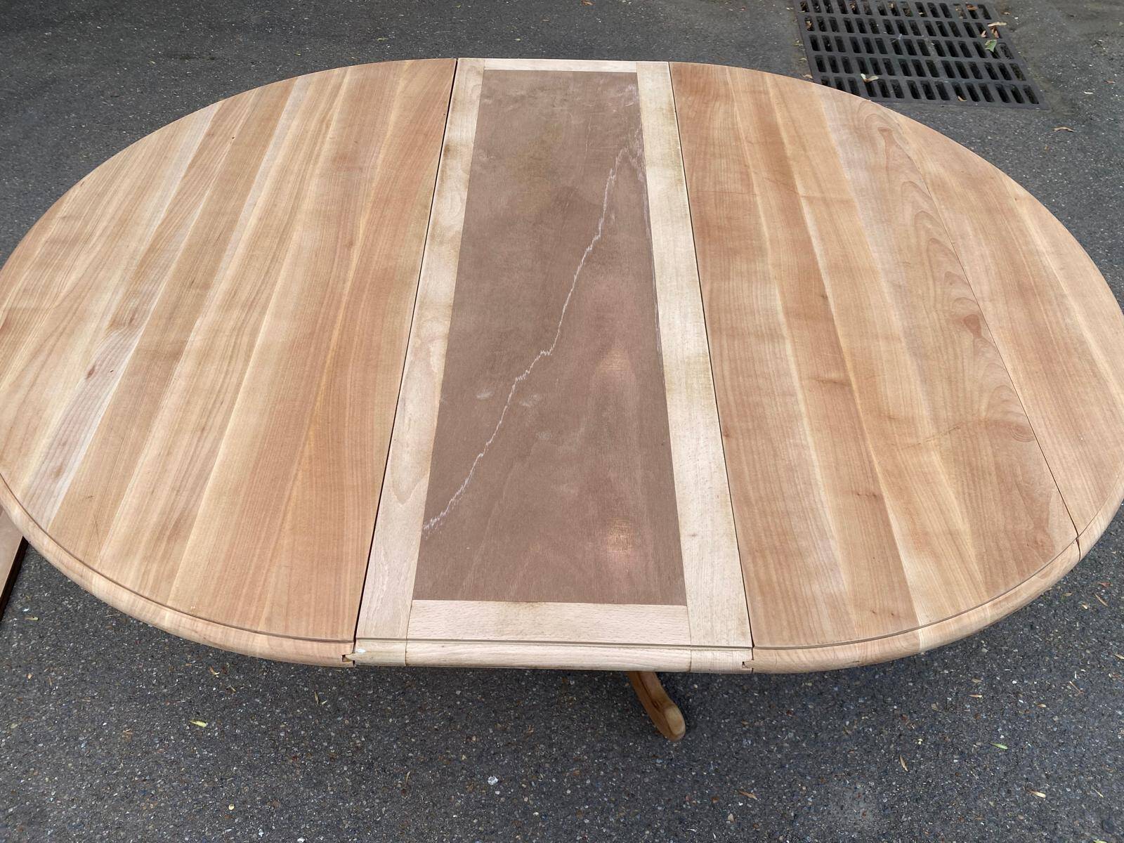 Round dining table with a central pedestal, extendable, stripped in solid walnut with 2 extensions.