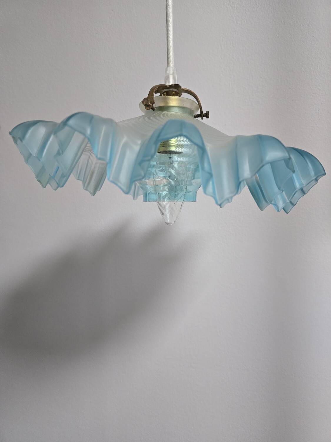 Suspension lampshade with scalloped edges in blue and its interior decoration.