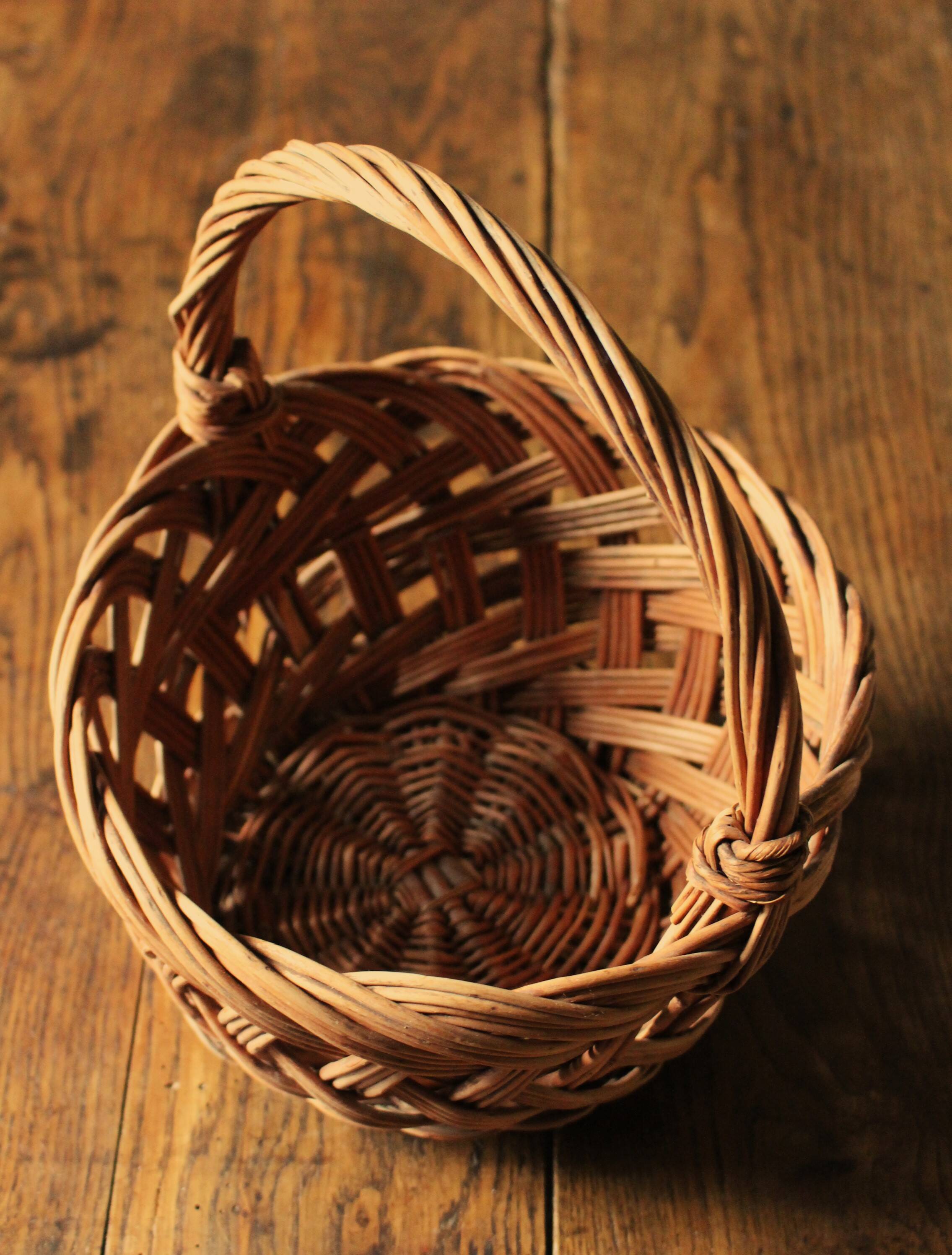 Round woven dark wicker basket with openwork vintage handle