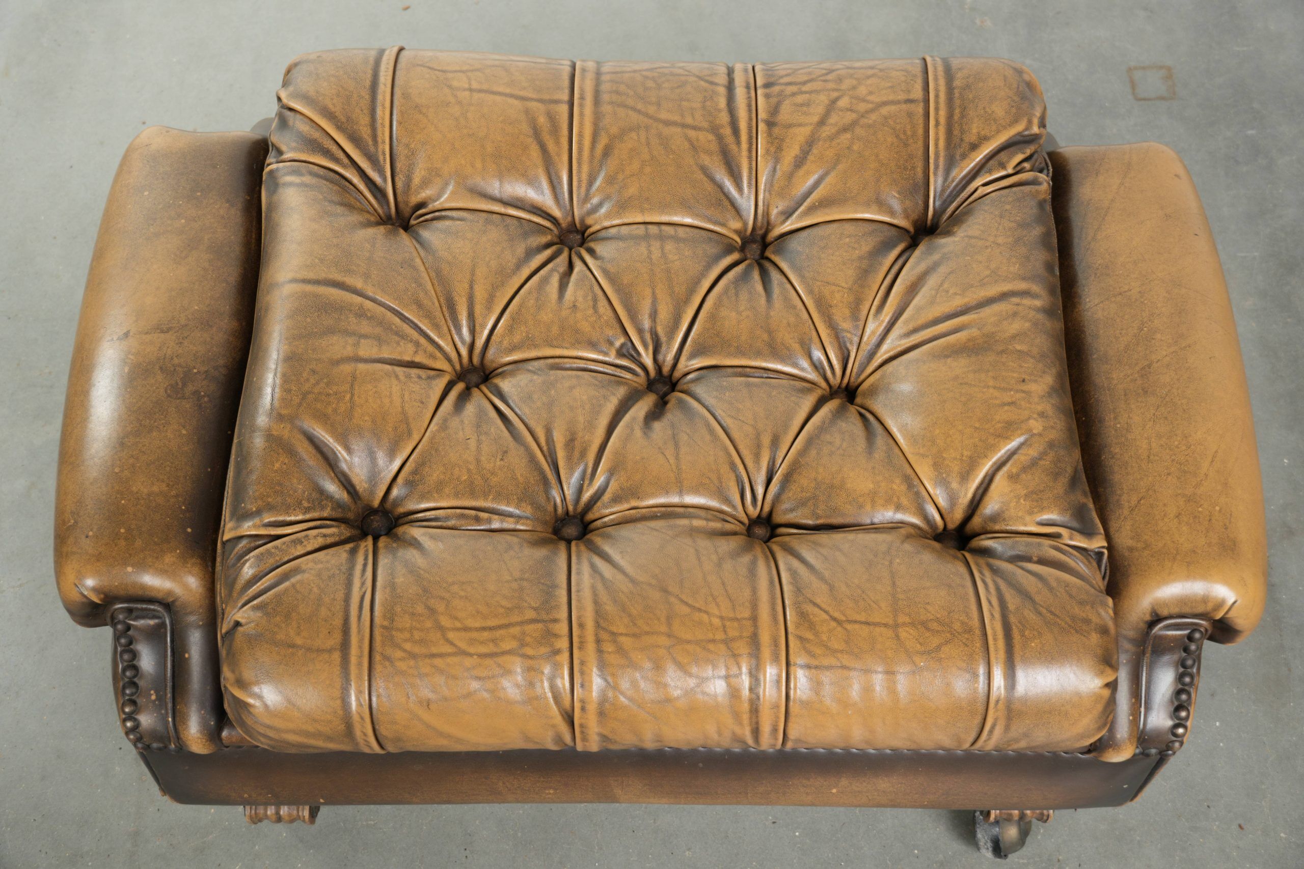 Ottoman chesterfield anglais en cuir élégant, fini avec des clous décoratifs.