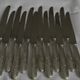 Set of 12 knives with silver metal handles and stainless steel blades.