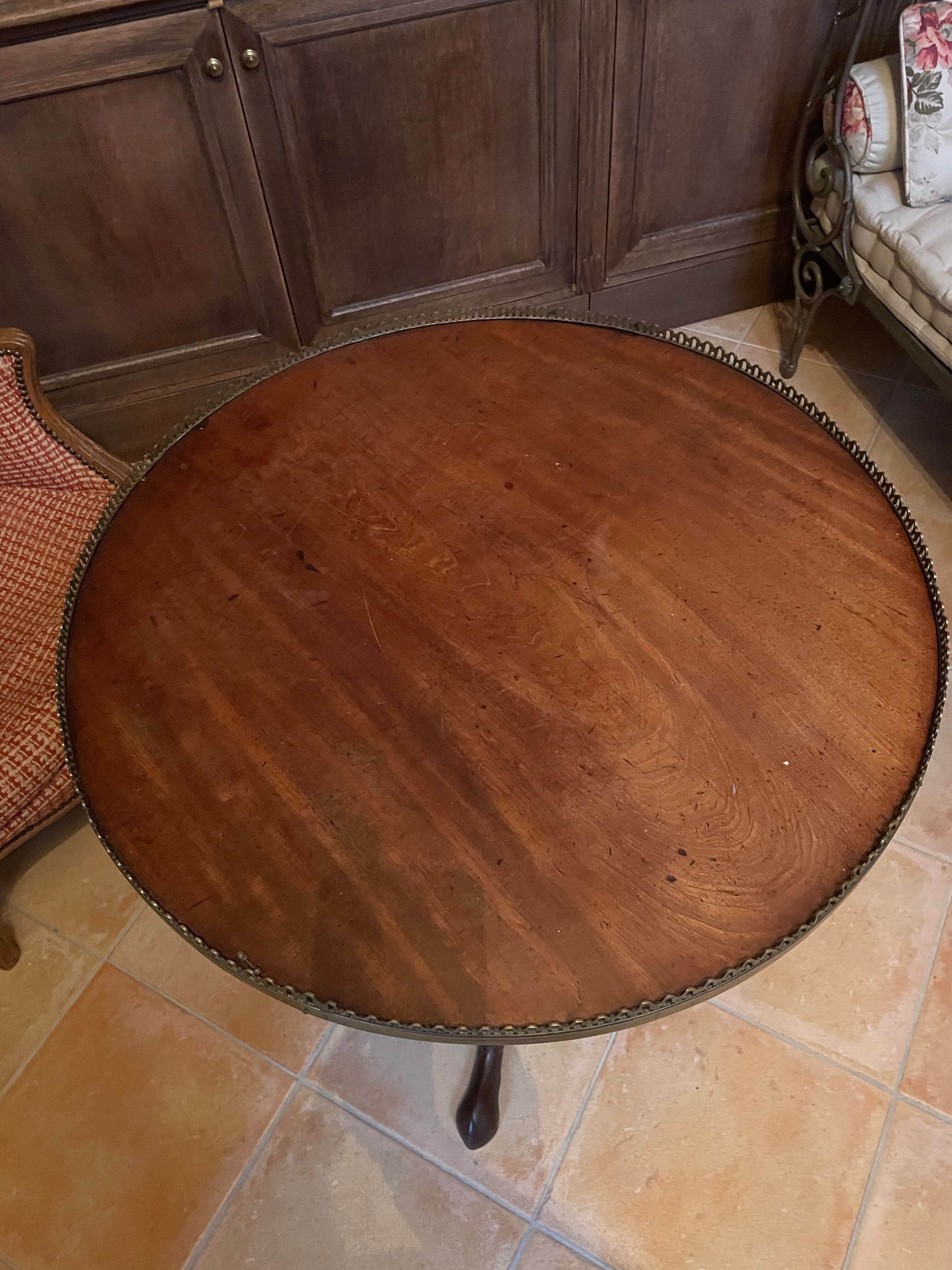 Foldable tripod side table in carved mahogany with brass trim.