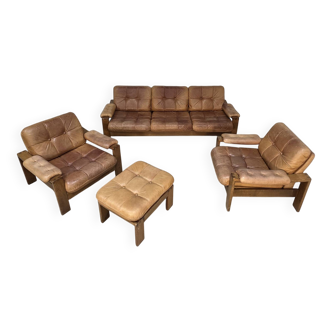 A lovely living room set comprising a pair of armchairs, a tan leather sofa and its ottoman