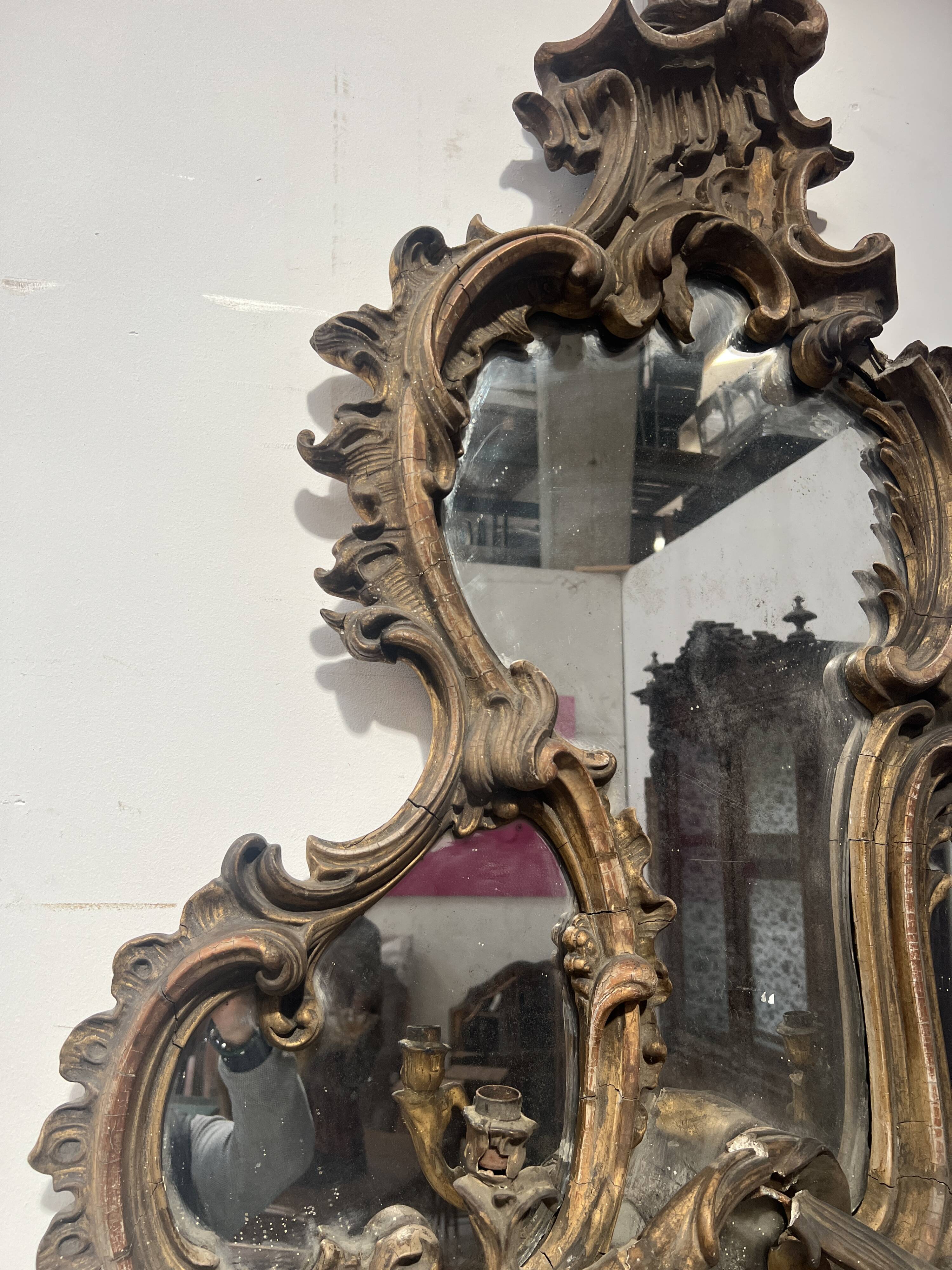 Mirror with a decorative frame featuring a four-light wall sconce, 19th century.