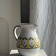 Large white terracotta carafe with a stylized green and yellow frieze pattern