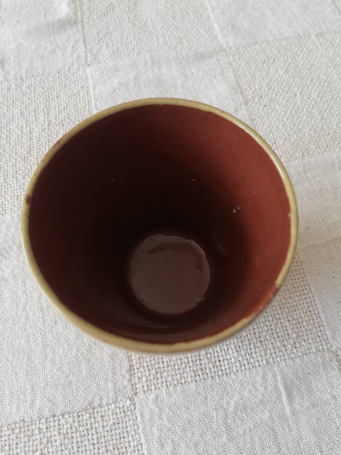 Mustard-colored ceramic cup or glass with green decor
