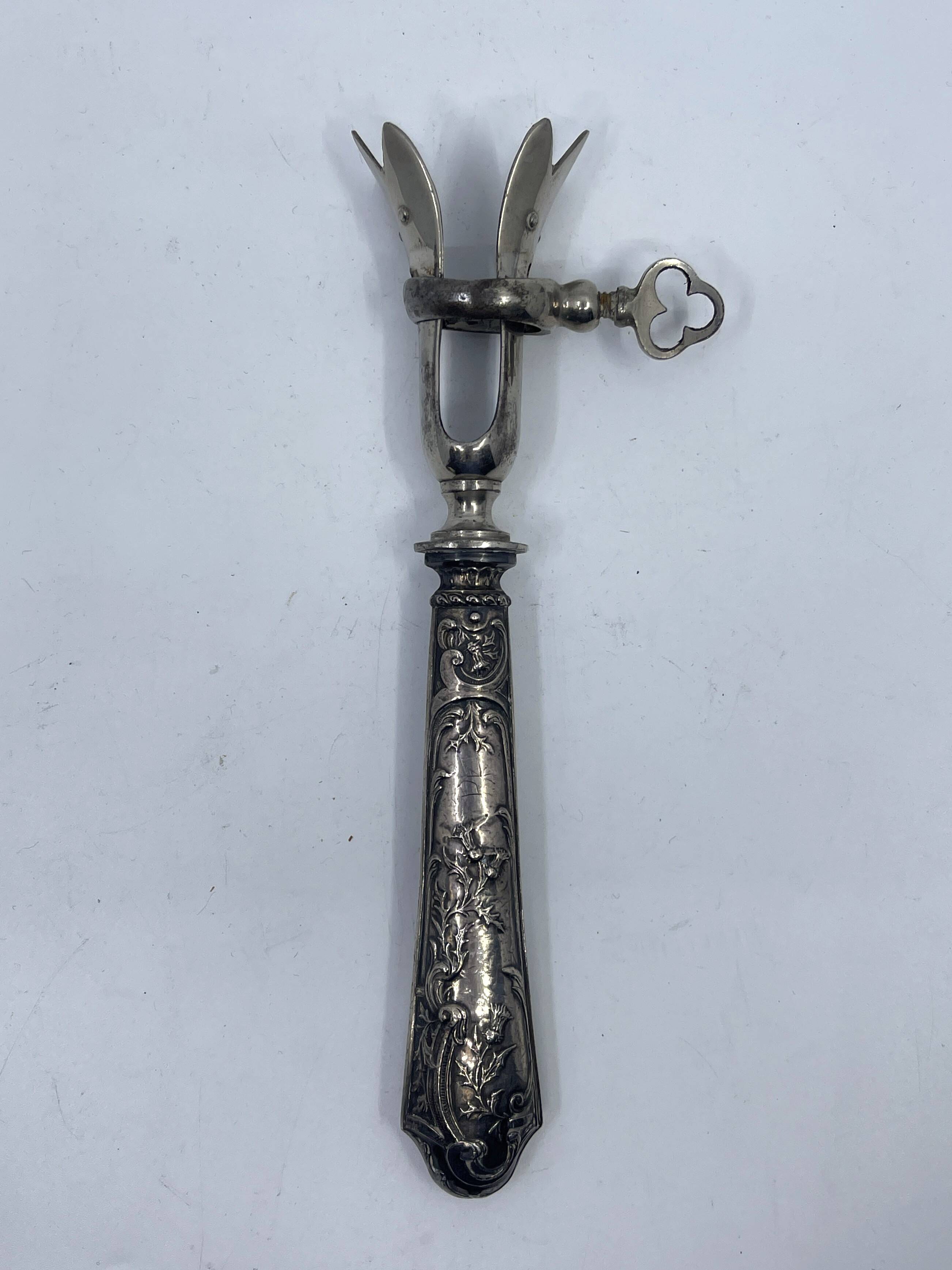 Silver-plated metal leg of lamb handle with engraved thistle flower patterns.