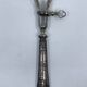 Silver-plated metal leg of lamb handle with engraved thistle flower patterns.