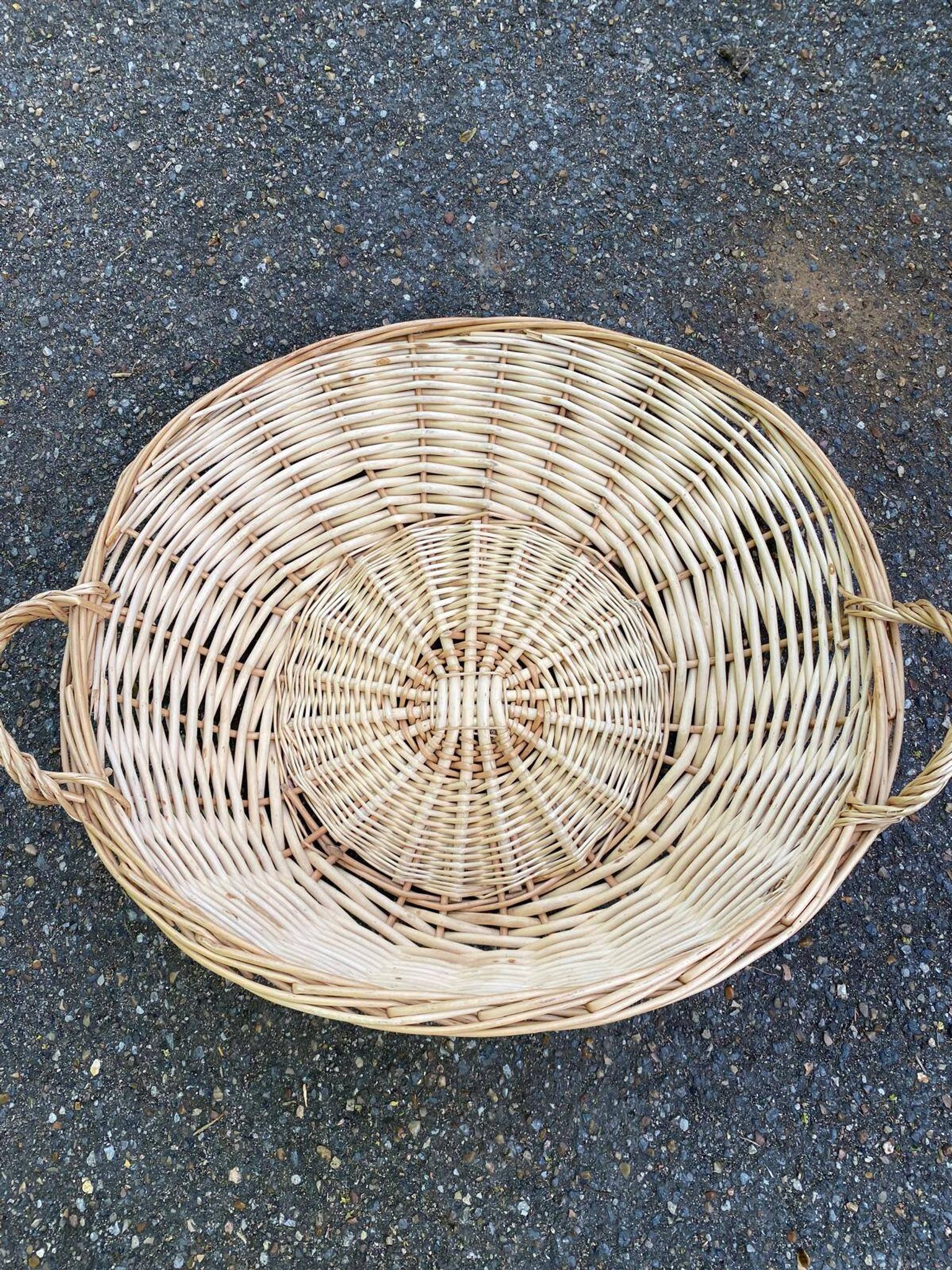 Round presentation basket made of woven wicker and rattan.