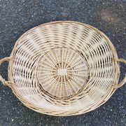 Round presentation basket made of woven wicker and rattan.