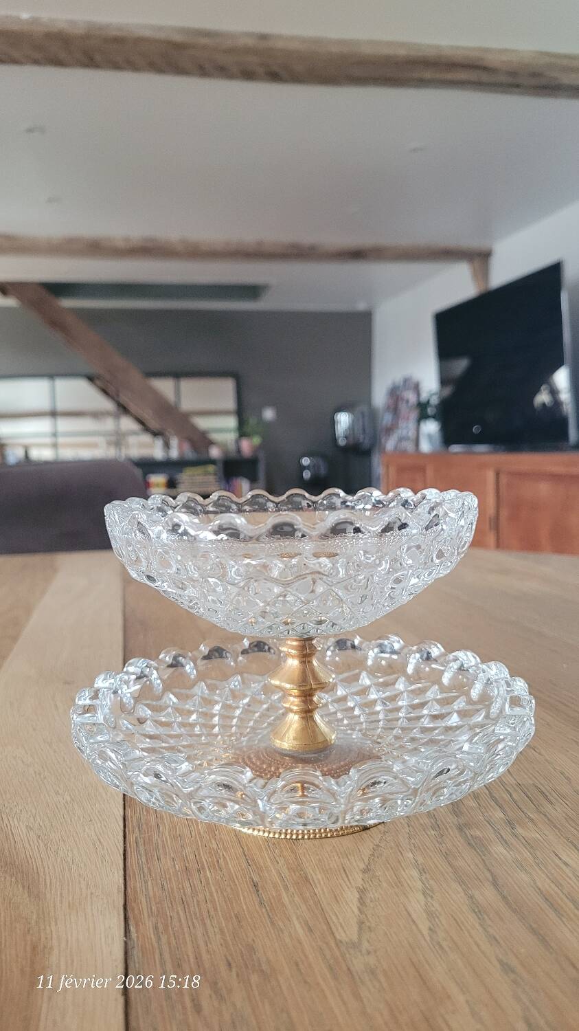 Two-tier display stand in cut glass mounted on a gold metal base.