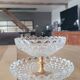 Two-tier display stand in cut glass mounted on a gold metal base.