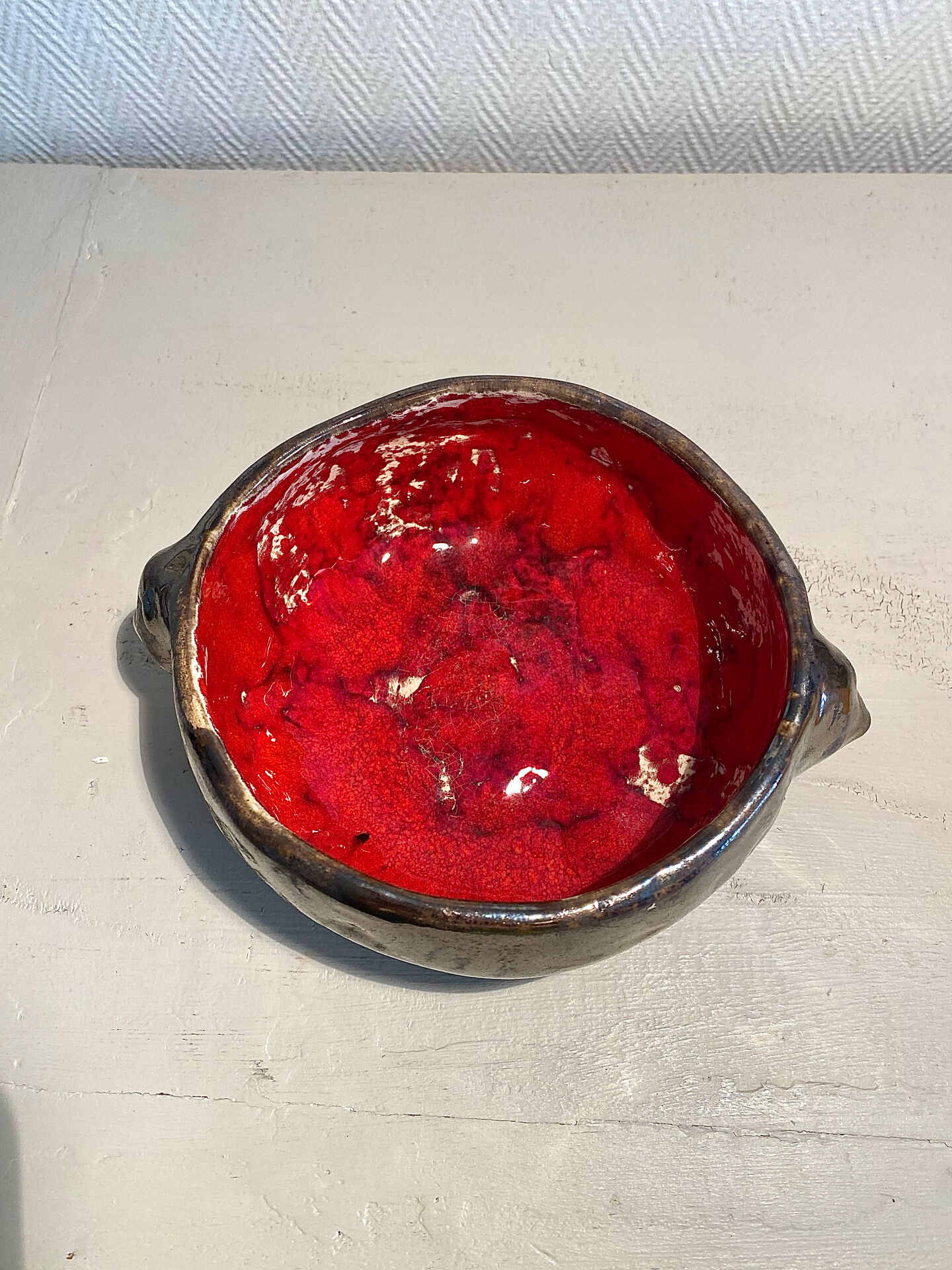 Deep red glazed and metallic ceramic catchall.