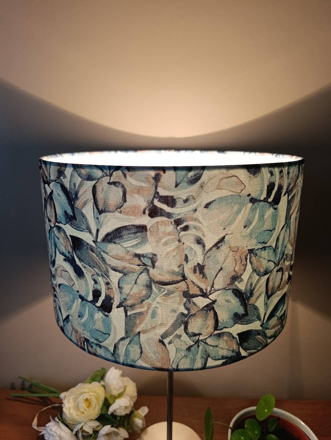 Table lamp with chrome stem, tropical plant shade.