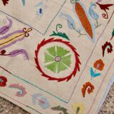 White suzani kilim rug with embroidered multi-colored patterns