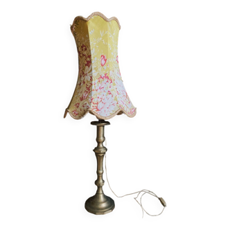 Old lamp with yellow flowered lampshade and brass base.