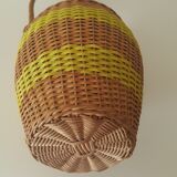 Vintage glass bottle covered with hand-woven wicker and scoubidou, with a handle