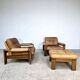 A lovely living room set comprising a pair of armchairs, a tan leather sofa and its ottoman
