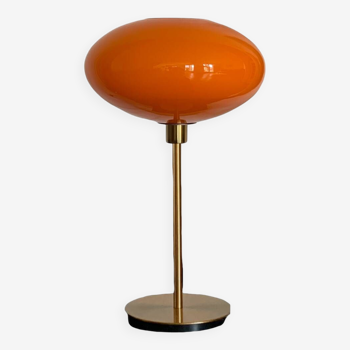 Table lamp with a vintage orange glass globe saucer and a gold base