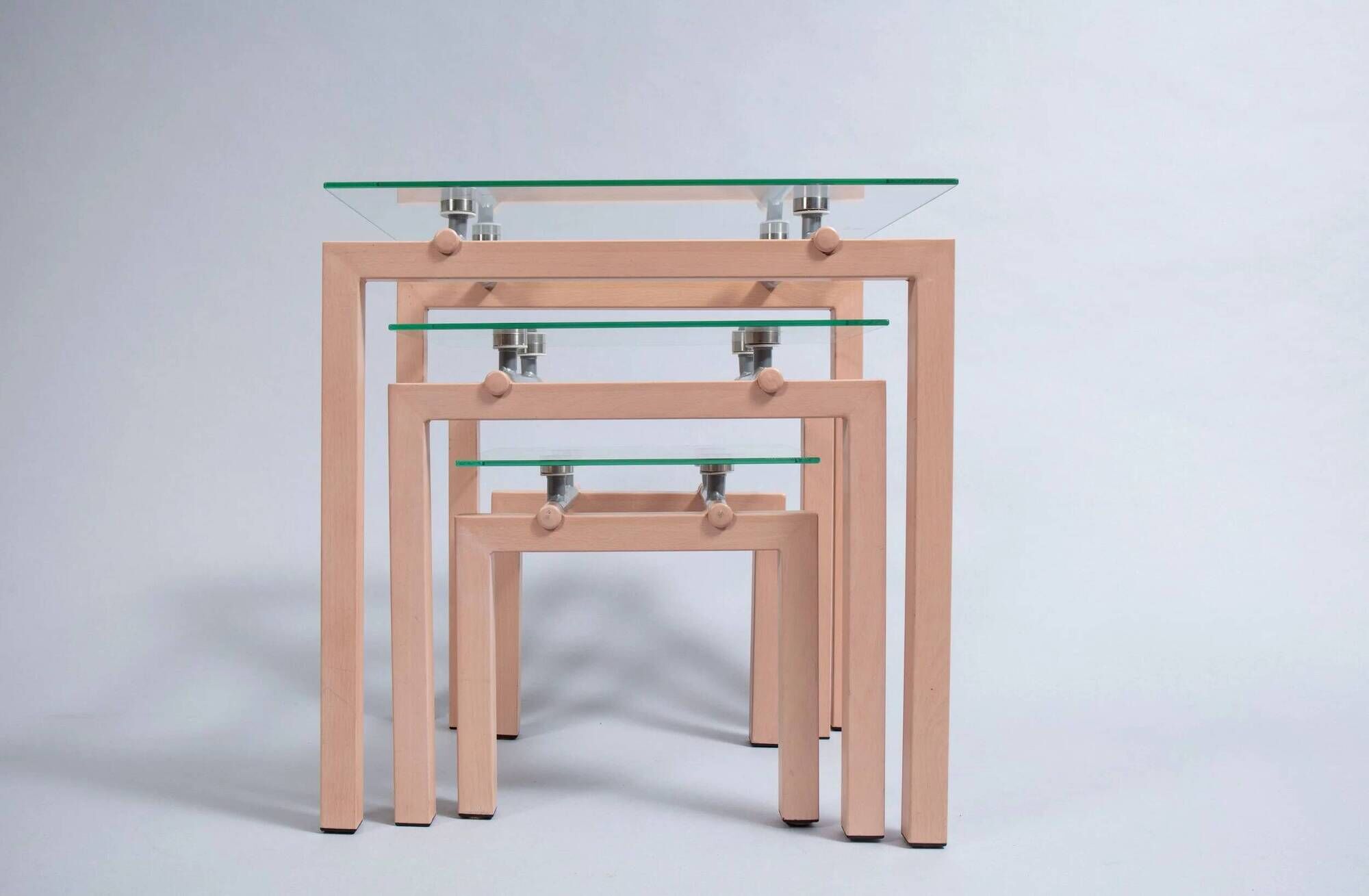 Three nesting tables from the 90s made of painted metal and tempered glass.