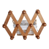 Antique wall-mounted coat rack accordion in dark pine, 10 wooden hooks.