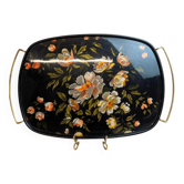 Large vintage 1960s platter with floral decoration on a black background and golden handles.