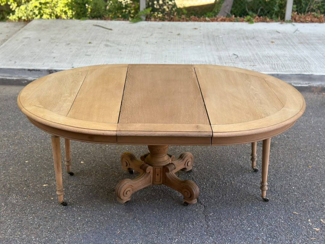 Round dining table with a central pedestal, stripped raw oak, 4 extensions, 19th century.