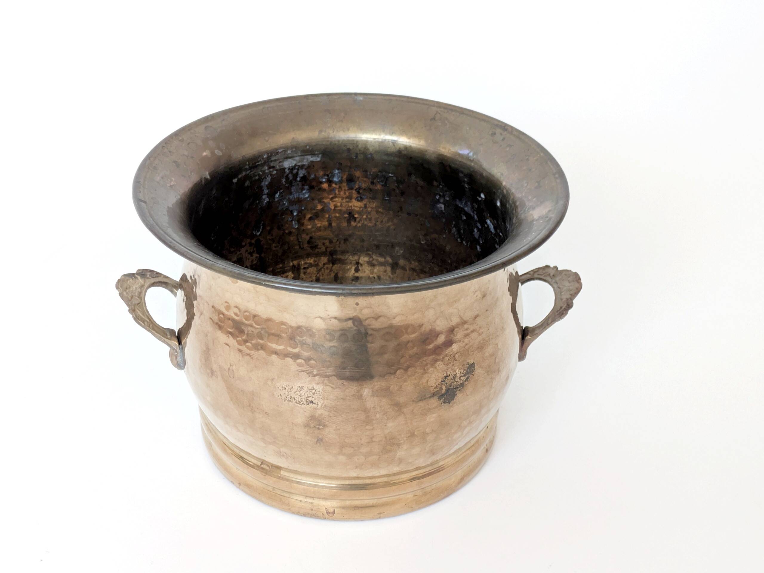 Vintage round cache-pot in hammered brass with decorative handles and patina.