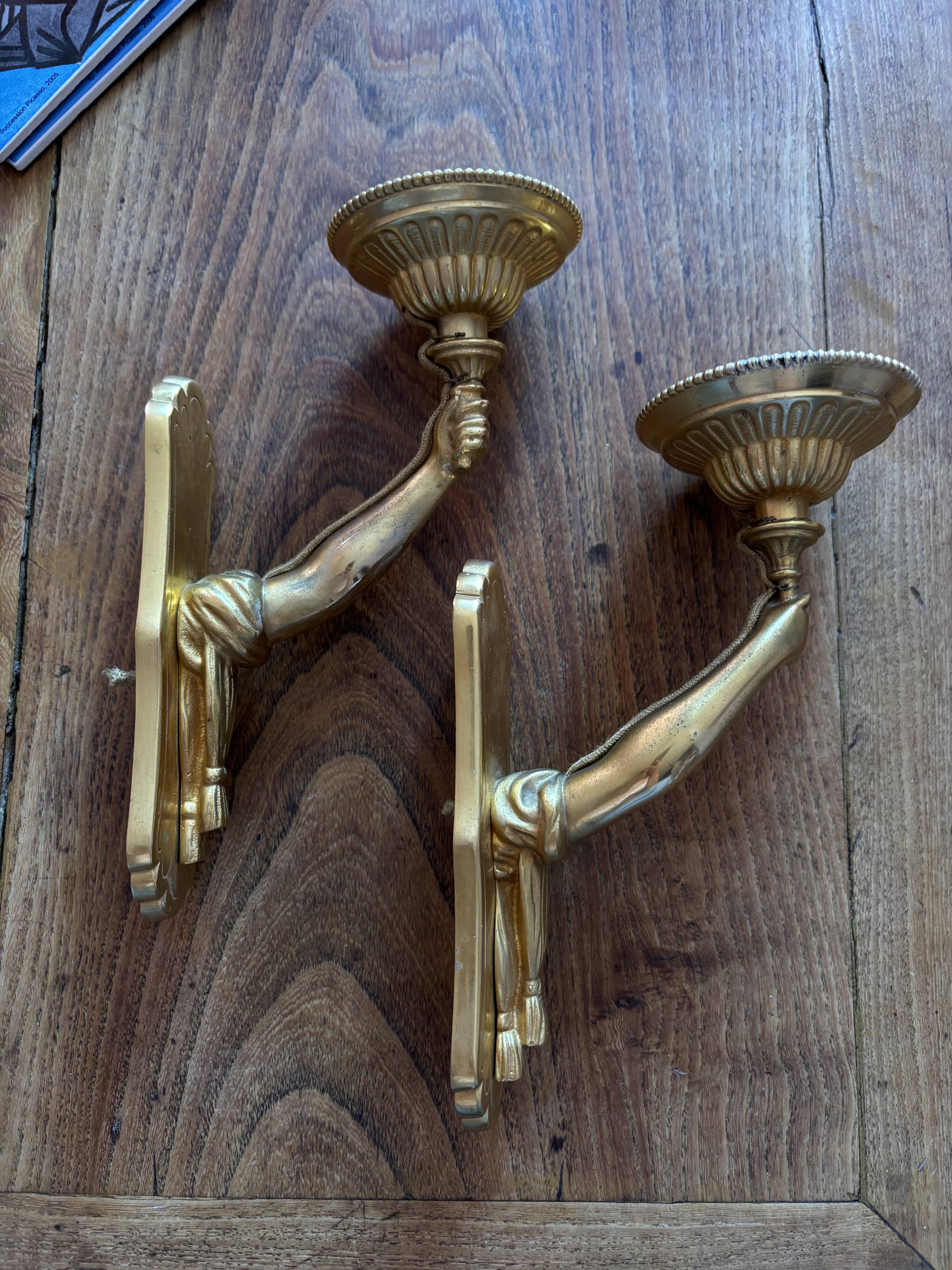 Pair of bronze wall sconces with outstretched arms and hands