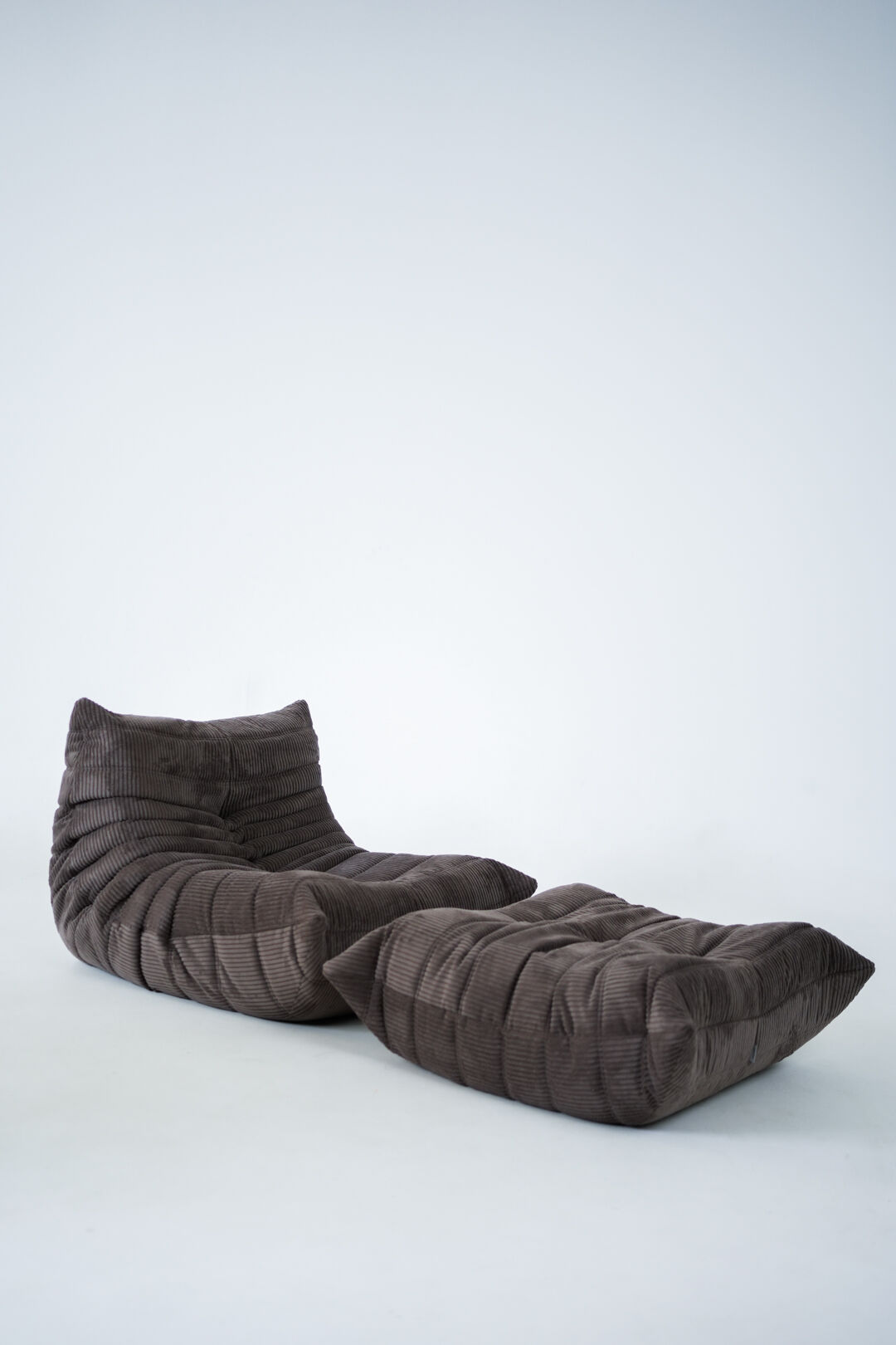 Ensemble de chaise et pouf Togo en velours côtelé marron.