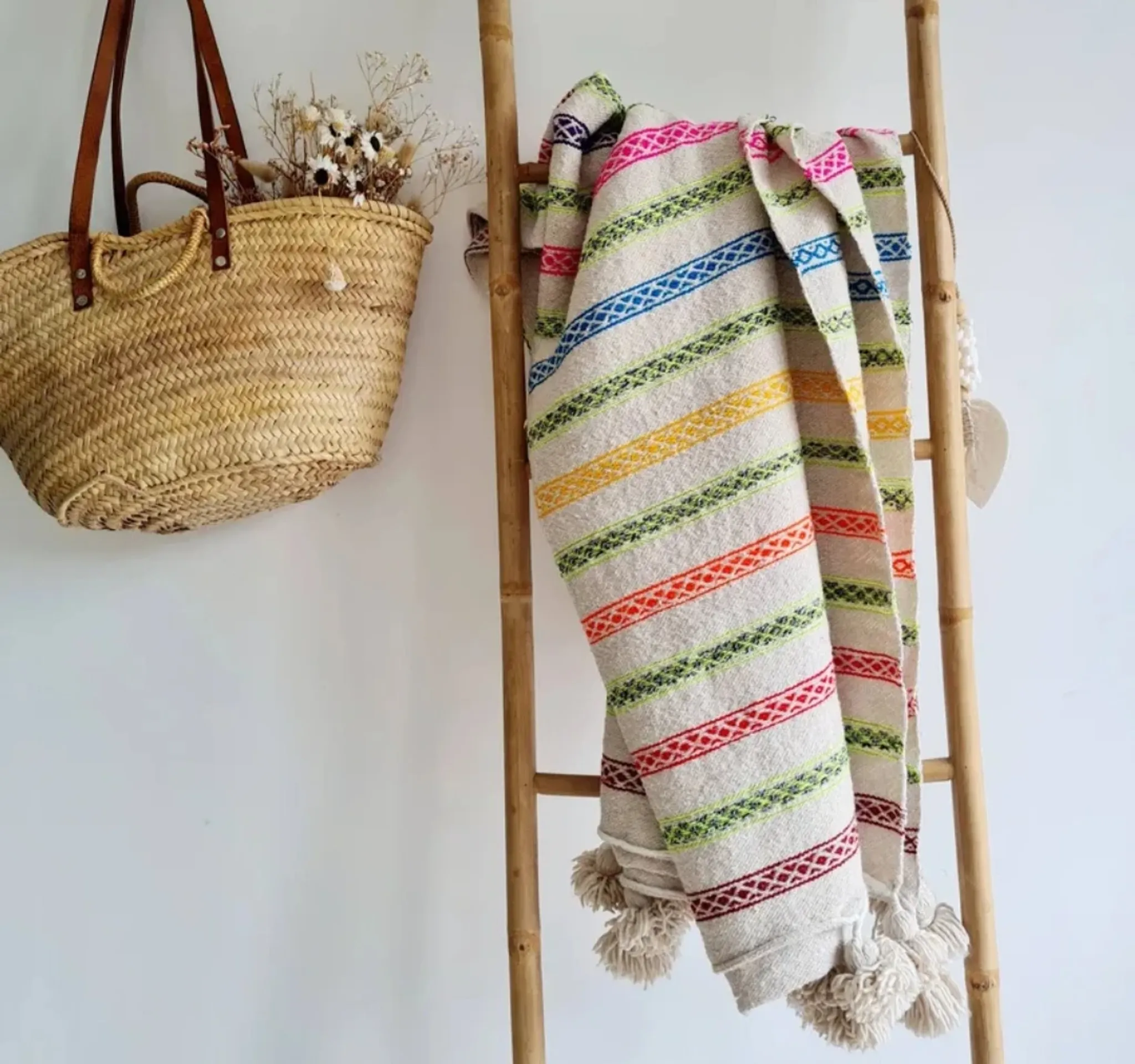 Moroccan plaid made of handwoven wool, decorated with stripes and pom poms.