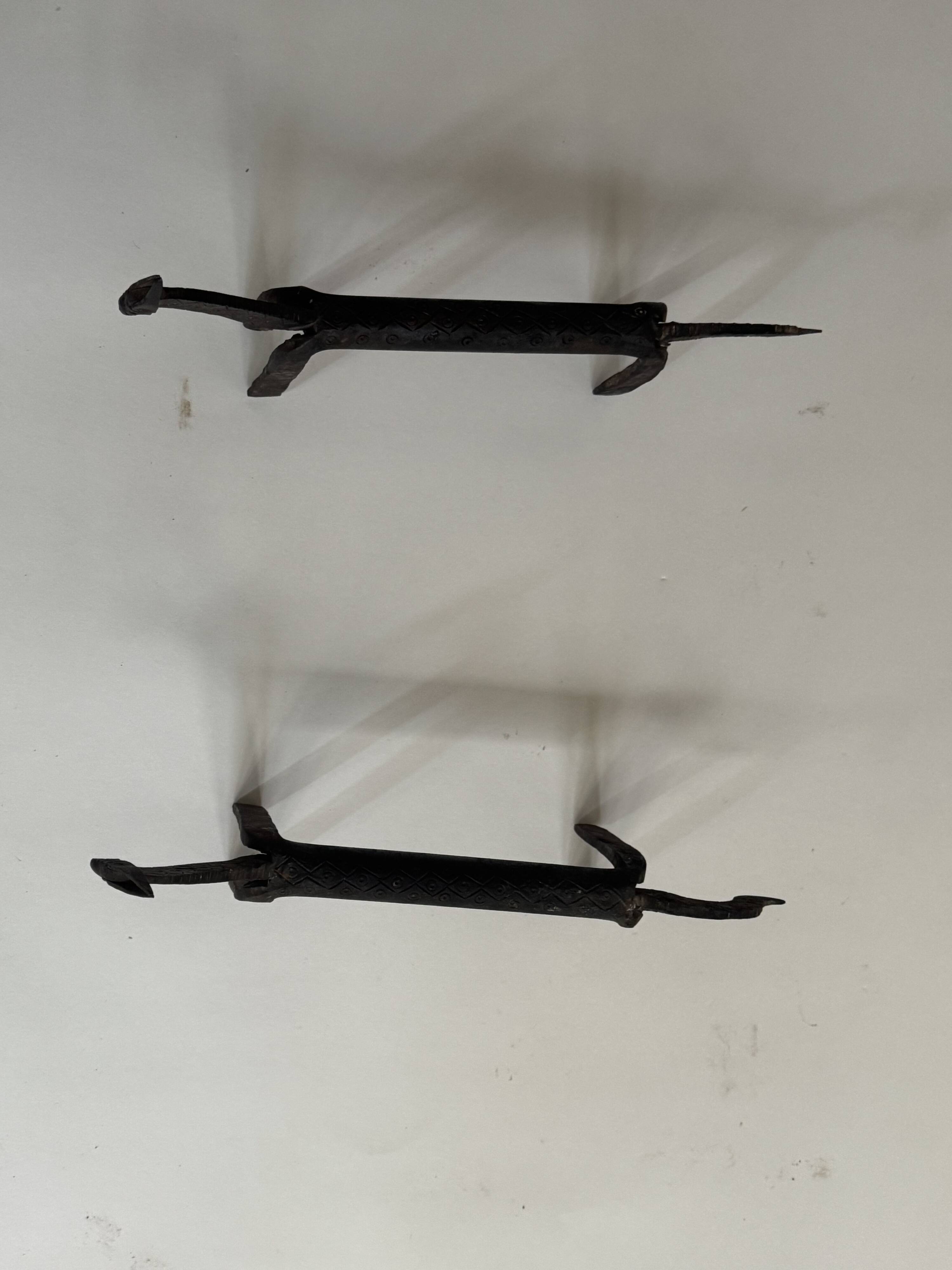 Pair of animal-shaped wrought iron and hammered fire dogs in primitive brutalist style.