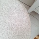 Black iron stool/pouf with its boucle fabric cushion.