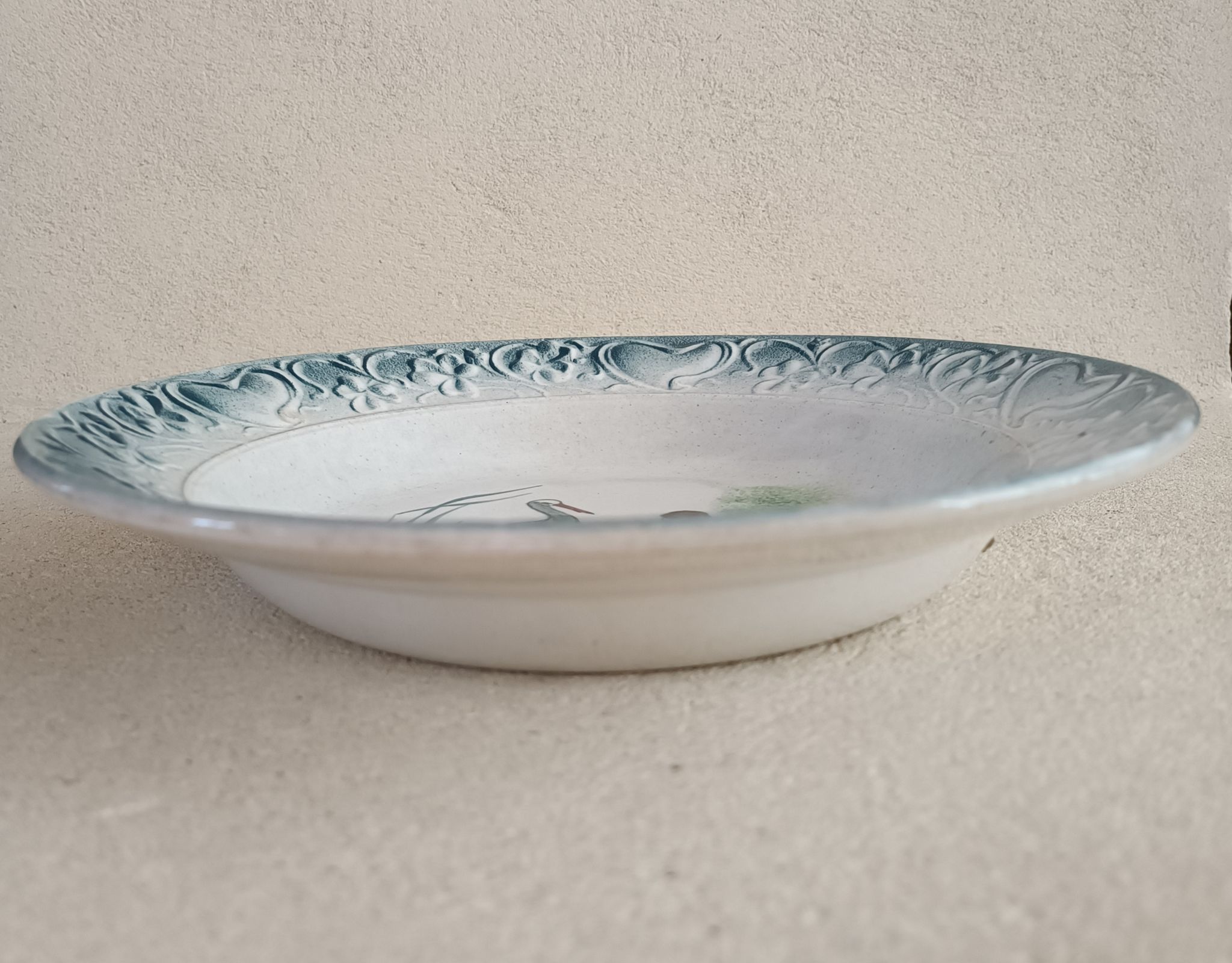 Plat de service terre de fer à décor d'enfant et cigogne