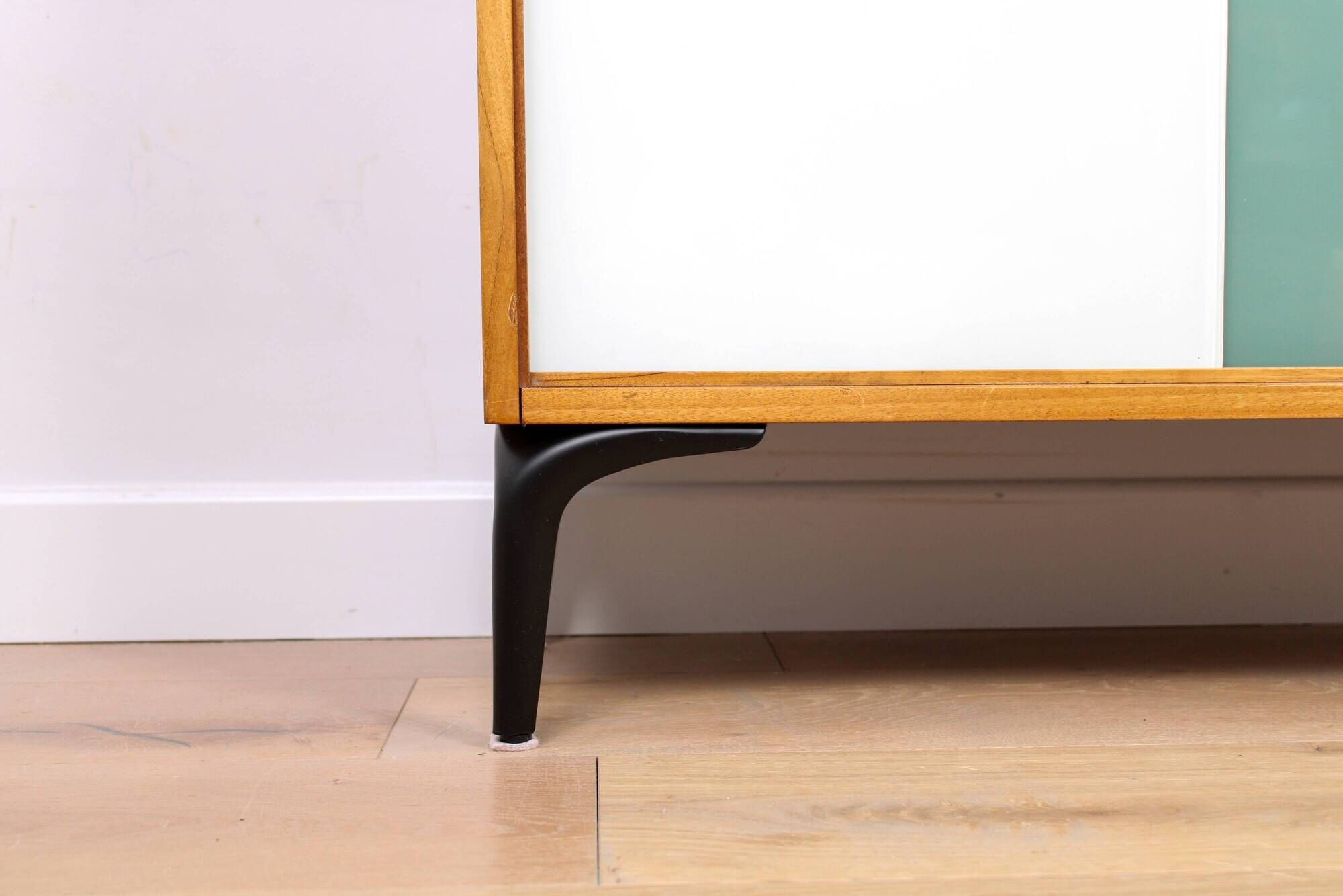 A vintage mid-century bookshelf/sideboard with green and white sliding door