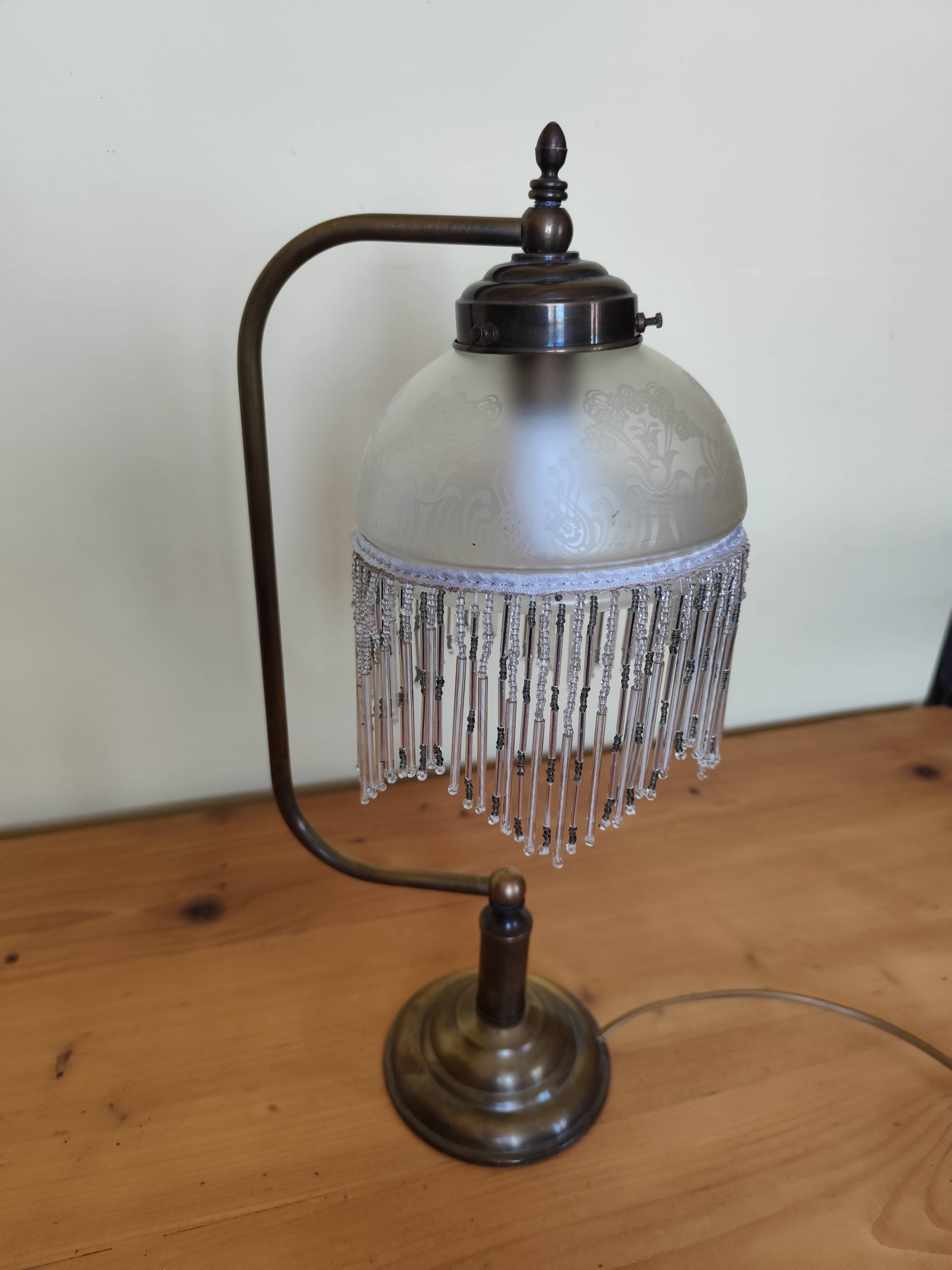 Retro brass lamp with a glass shade and bead fringes.