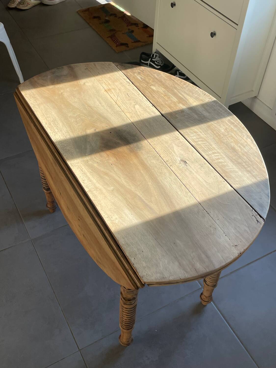 Oval wooden table with drop-leaf edges.