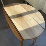 Oval wooden table with drop-leaf edges.