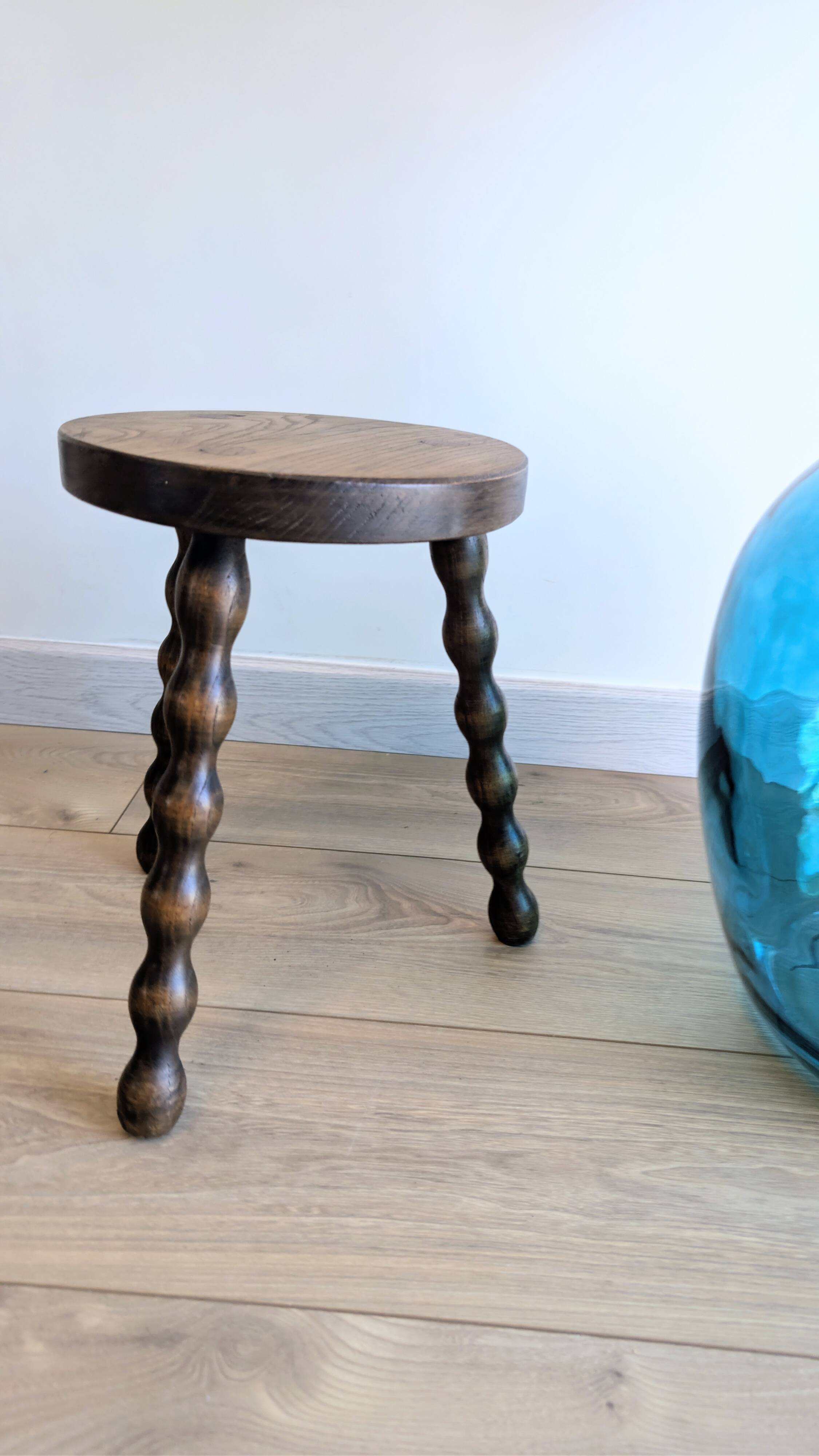 Small wooden tripod stool with turned legs, country style.