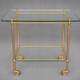 Service trolley on wheels with two glass shelves and a brass frame.