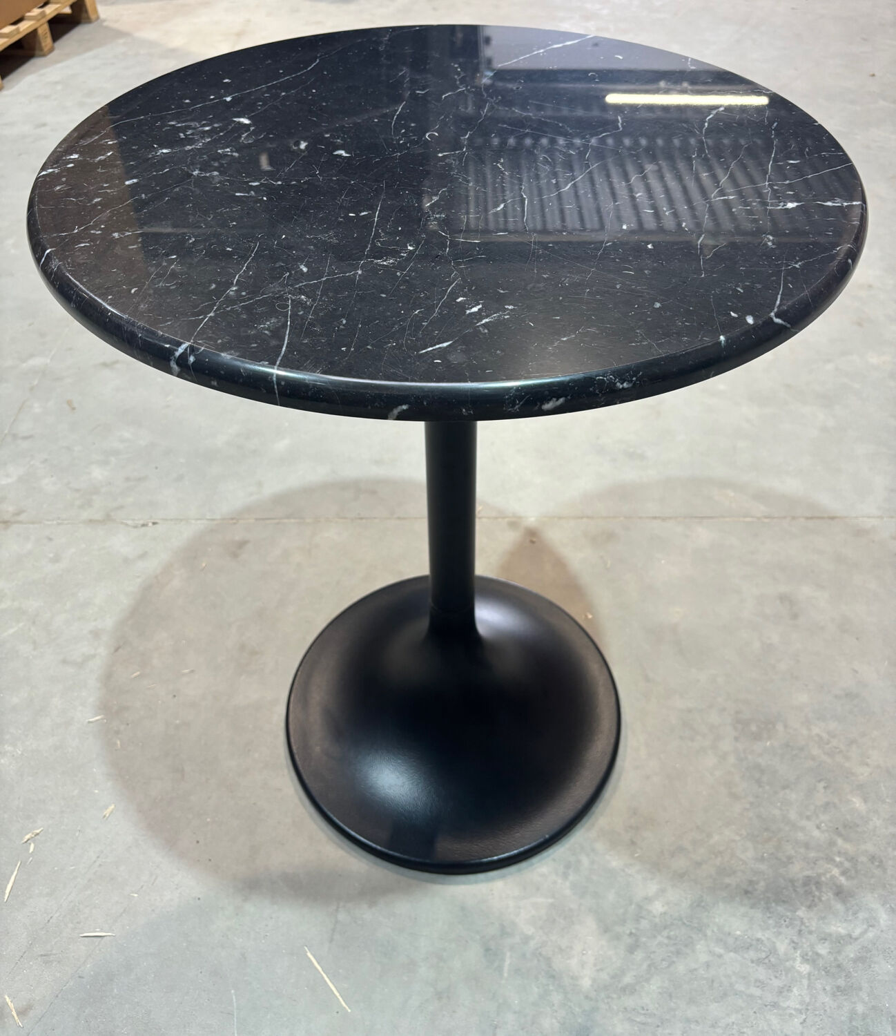 Round marble table with a black metal tulip base.