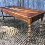 Antique farmhouse table in solid cherry wood with turned legs.