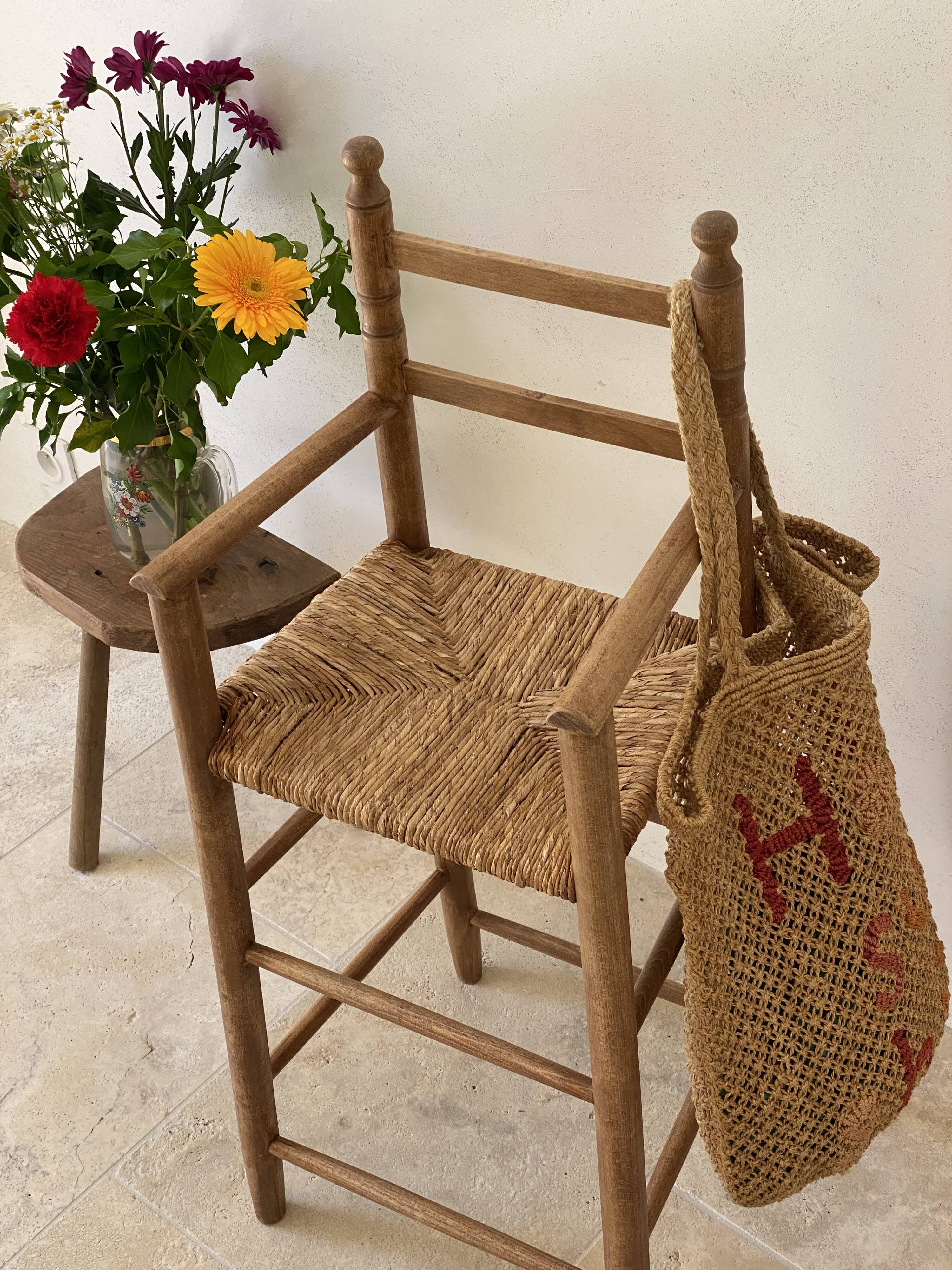 Old wooden high chair for children with a straw seat.